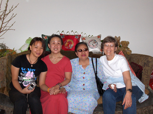 Ann, Nanta, Sarah and Dona sit on the couch, smiling at the camera.